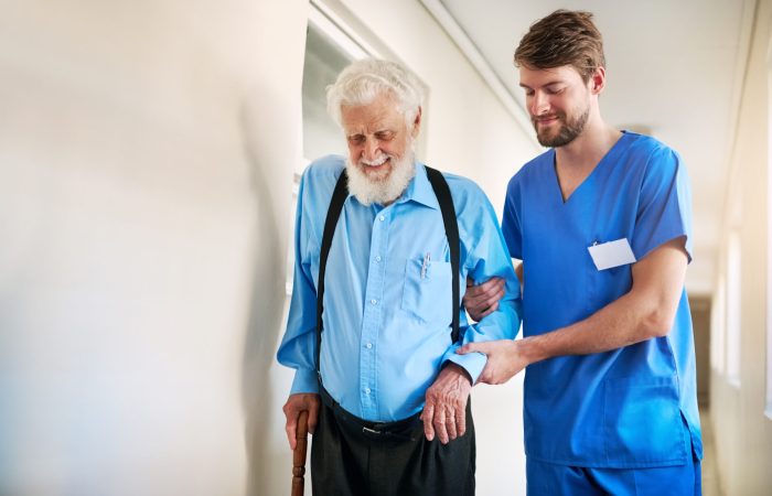 Shot of a young doctor helping his senior patient walk down a hallway in hospital